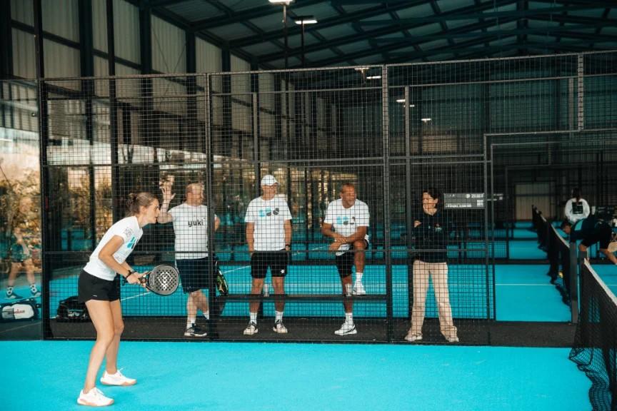 Spelers en coach op een blauwe clubbaan tijdens een training